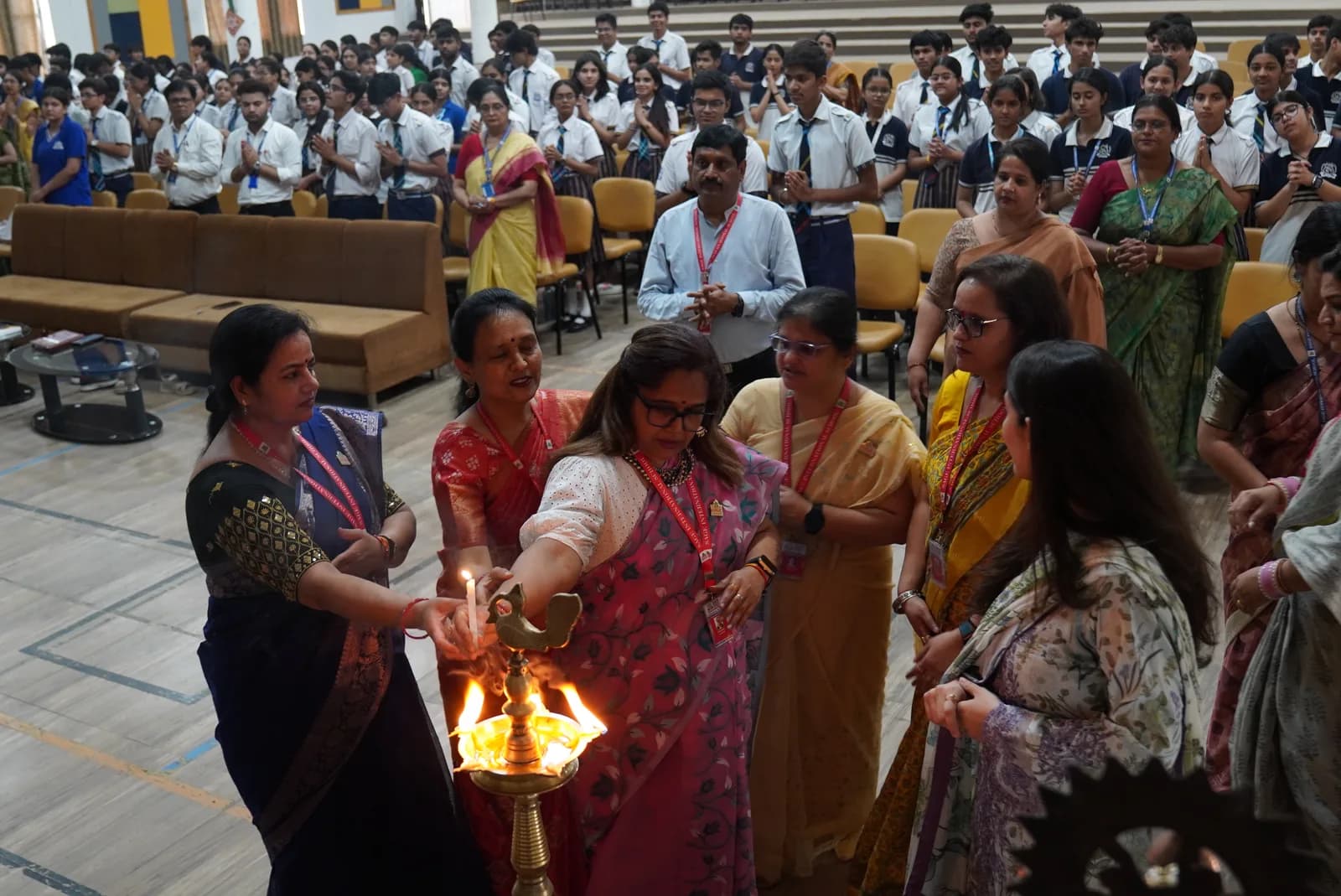 School community members gathered around a ceremonial lamp in an auditorium