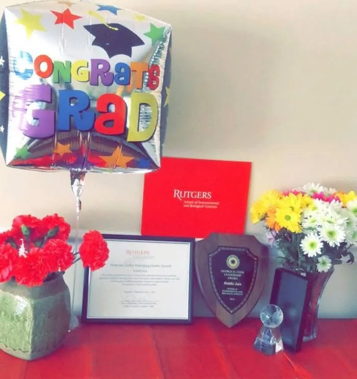 A framed award, a plaque and flowers beside a 'Congrats Grad' balloon