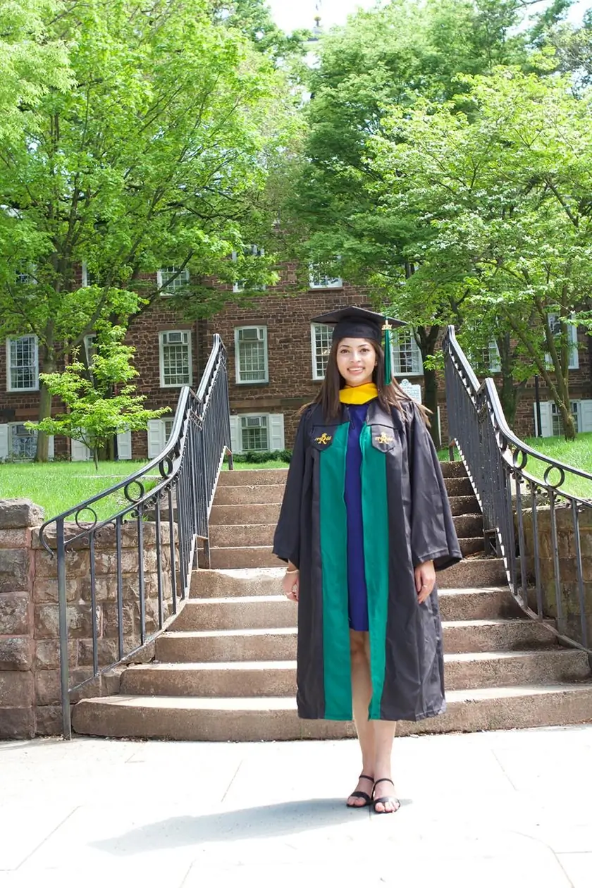 Bhakti in a graduation gown on the steps of a university building